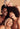 Four women with diverse hair and skin tones smiling together against a beige background