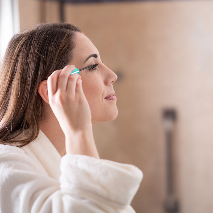 Woman in bathroom applying FACTORFIVE Lash/Brow Growth Serum